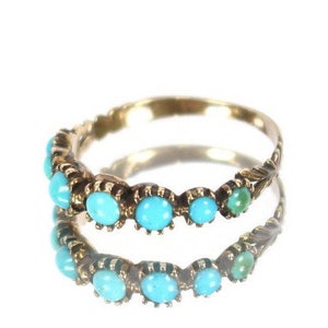 May include: A gold band ring with a row of turquoise stones set in the band.