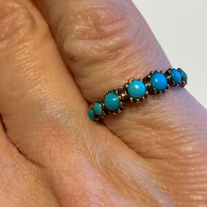 May include: A gold ring with a row of turquoise stones set in a bezel setting.
