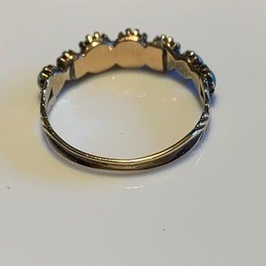May include: A gold ring with a row of turquoise stones set in silver.