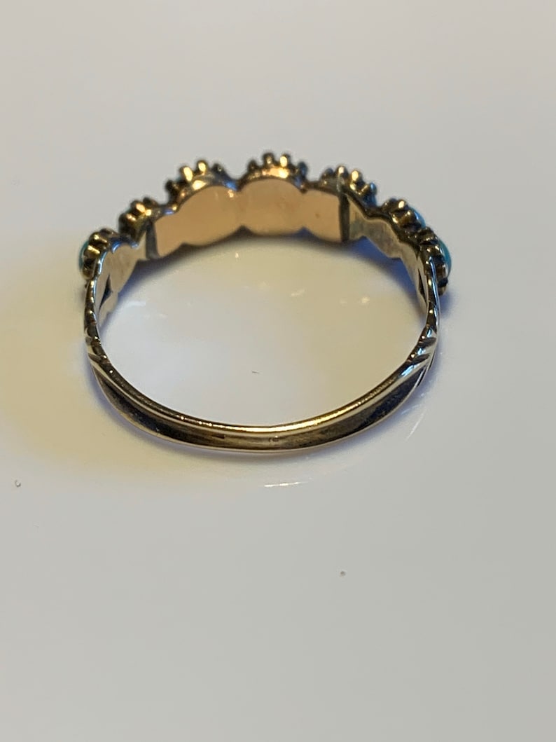 May include: A gold ring with a row of turquoise stones set in silver.