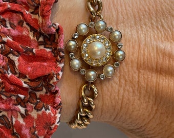 May include: A gold chain bracelet with a pearl and diamond cluster pendant. The pendant is a circular design with a large pearl in the center surrounded by smaller pearls and diamonds.