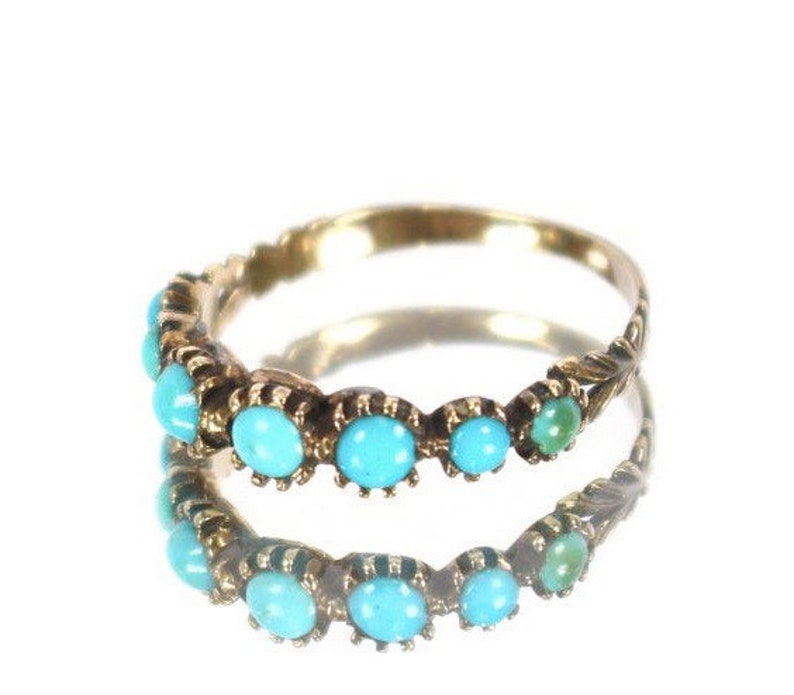 May include: A gold band ring with a row of turquoise stones set in the band.