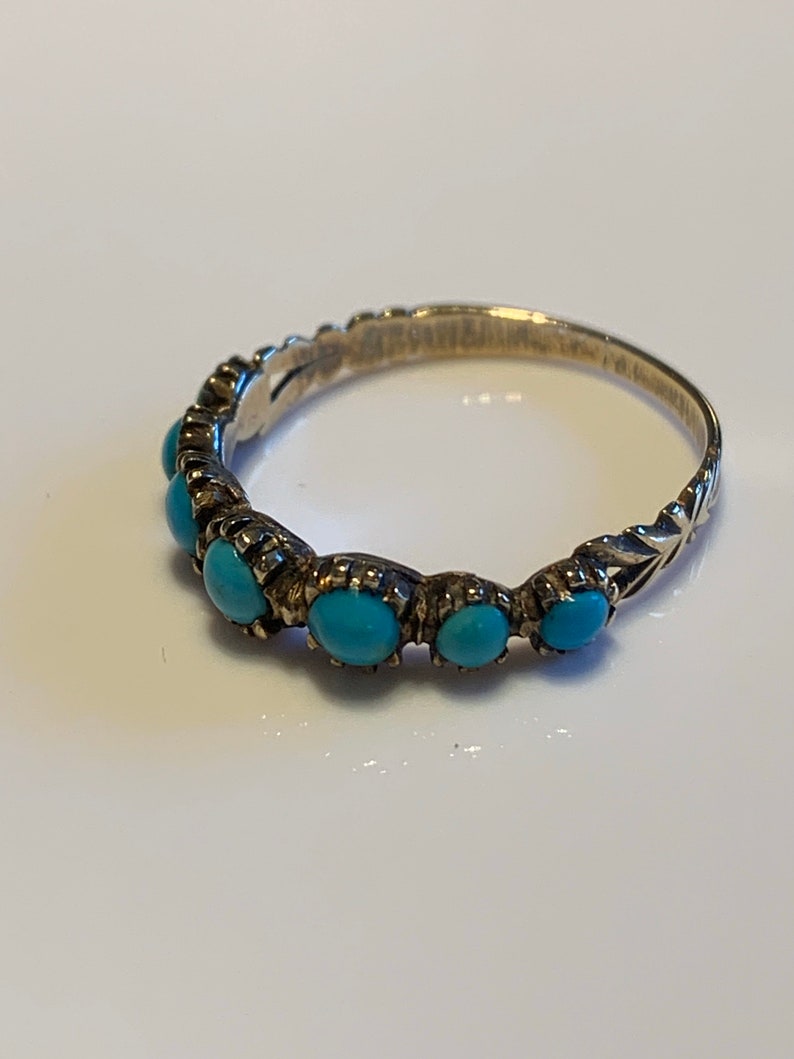 May include: A silver ring with a row of turquoise stones set in the band.