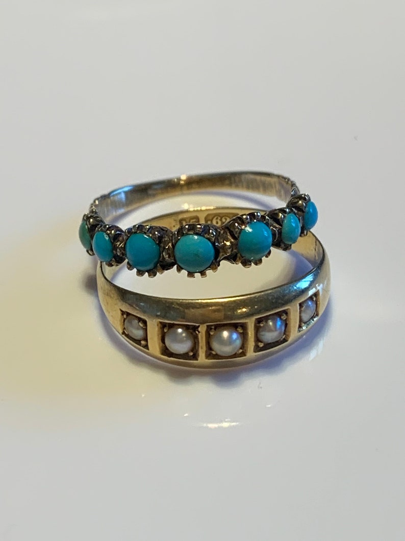 May include: Two gold rings with turquoise and pearl stones. The top ring has a row of turquoise stones set in a gold band. The bottom ring has a row of pearls set in a gold band.