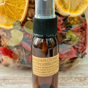 May include: A small brown glass bottle with a black spray nozzle and a yellow label that reads "Balsam Cedar Potpourri Spray". Directions for use are printed on the label: "Spread potpourri on paper towels or an old rug. Spritz oil evenly over the potpourri. Let air dry several minutes."