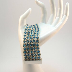 May include: A blue and silver beaded bracelet with a silver clasp. The bracelet is made with small, round beads and square beads.
