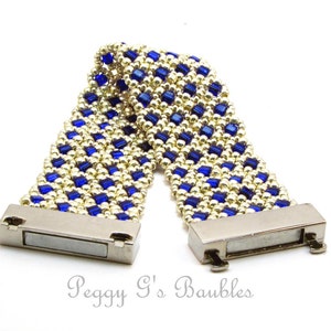 May include: A gold and blue beaded bracelet with magnetic clasps. The bracelet is made with small, square beads in a checkered pattern.