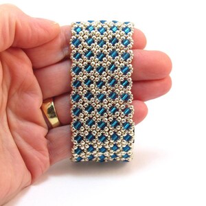 May include: A blue and gold beaded bracelet with a geometric pattern.