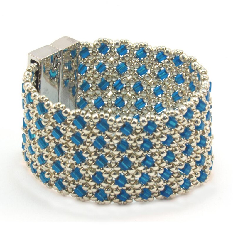 May include: A silver and blue beaded bracelet with a silver clasp. The bracelet is made with small, square beads in a geometric pattern.