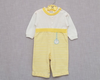 May include: A yellow and white striped baby onesie with a white top and a yellow band around the waist. The onesie has a small blue and white embroidered design of a pocket watch on the front.