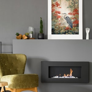 Puede incluir: Una chimenea gris con un marco negro y un fuego ardiendo en su interior. Sobre la chimenea hay una impresi&oacute;n enmarcada de una garza azul de pie en un bosque con flores rojas.