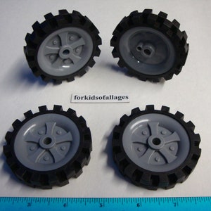 May include: Four gray plastic wheels with black rubber tires. The wheels have a five-spoke design and a central hole.