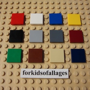 May include: A collection of twelve square Lego bricks in various colors, including red, white, blue, yellow, black, gray, dark red, green, brown, beige, and navy blue. The bricks are arranged on a tan Lego base. The text "forkidsofallages" is visible.
