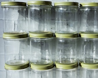 May include: A set of ten clear glass jars with olive green lids. The jars are stacked in three rows, with three jars in the top row, three in the middle row, and four in the bottom row.
