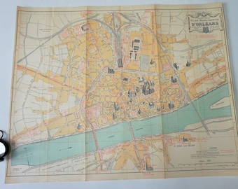 May include: A vintage map of Orléans, France, with the title "Plan Monumental D'Orléans" at the top. The map features a detailed layout of the city, including streets, buildings, and the Loire River. The map is folded and has a grid pattern.