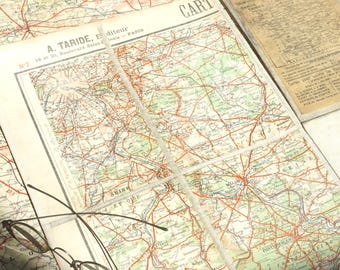 May include: A vintage map of France with red and blue lines, showing rivers and roads. The map is titled "Nouvelle Carte de France" and is labeled "A. Taride, Editeur" with an address in Paris. A pair of eyeglasses is resting on the map.