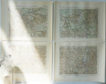 May include: Four vintage maps with detailed line work, featuring shades of brown, beige, and green. The maps are displayed on aged paper, with visible text and grid lines. A glass jar with a decorative lid is in the foreground.
