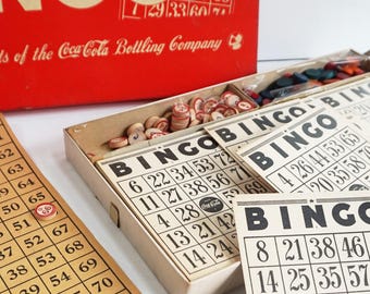 May include: Vintage Coca-Cola Bingo game in a red box with wooden chips, cards, and a small container of plastic chips. The cards have the numbers 1-75 and the words "Bingo" printed on them.