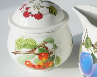 May include: White ceramic sugar bowl with a lid. The bowl features a floral design on the lid and a cherry branch design on the body.