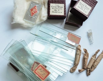 May include: A stack of 22x40 mm non-corrosive cover glass slides, wrapped in brown paper, with two boxes labelled "Cover Glass Non Corrosive No. 2 22x40 mm" and a small glass tube.