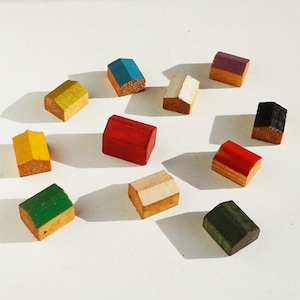 May include: Ten wooden toy houses in various colors, including red, blue, green, yellow, white, black, and purple. The houses are all different sizes and shapes, and they are arranged in a circle on a white surface.