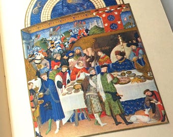 May include: A colourful illustration from a medieval manuscript showing a banquet. The image features figures in period dress, a table with food, and a celestial design in the background. The colour scheme includes blues, reds, and golds.