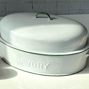 May include: White oval enamel roasting pan with a matching lid. The pan has green trim and handles, with the word "SAVORY" embossed on the side. A classic kitchenware item.