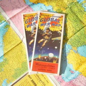 May include: Two vintage World War II global war maps with a dark blue background and illustrations of soldiers in military uniforms. The maps are titled "Global War Map" and "Global War" and are printed in red, white, and blue. The maps are from the Metropolitan Ludlow at Fourth Dayton, Ohio.