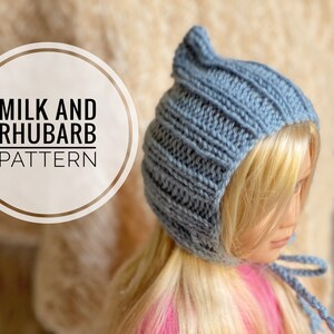 Puede incluir: Un gorro de punto azul con una parte superior puntiaguda y una larga corbata. El gorro se llama "Milk and Rhubarb Pattern".