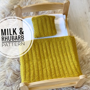 May include: A yellow knitted doll bed set with a blanket and pillow. The set is on a wooden doll bed frame. The text "MILK & RHUBARB PATTERN" is visible in the image.