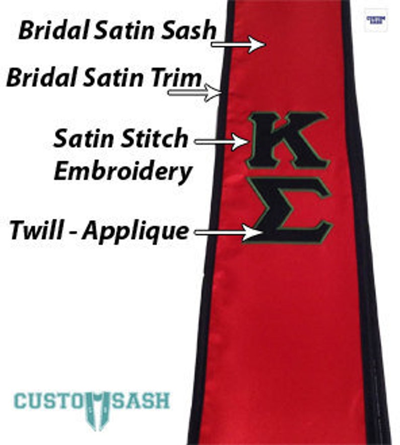 May include: Red satin sash with black trim and a black and gold applique of the letters "KL". The sash also features satin stitch embroidery.