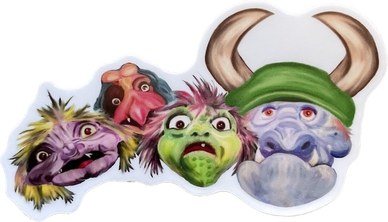 May include: A close-up of four colourful, furry monster puppets with large eyes. The puppets are arranged in a row, with the first puppet on the left having purple fur and yellow hair, the second puppet having pink skin and blue hair, the third puppet having green skin and pink hair, and the fourth puppet having blue skin and green horns.