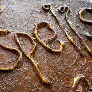 May include: A close-up of a sign with the word "Spells" written in gold lettering on a textured brown background.