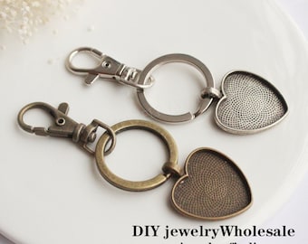 May include: Two silver keychains with heart-shaped charms. The charms are blank and have a textured surface. The keychains are attached to a silver split ring.