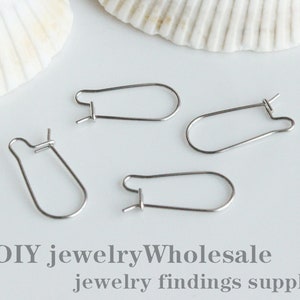 May include: Four silver earring hooks, also known as ear wires, are displayed on a white surface. The hooks are made of metal and have a simple, oval shape. DIY jewelry Wholesale jewelry findings supplies.