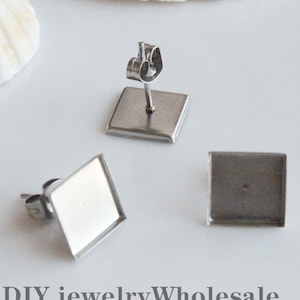 Könnte beinhalten: Drei silberne quadratische Ohrringrohlinge mit einem Stift und einem Schmetterlingsverschluss. DIY Schmuck Großhandel Schmuckfundstücke.