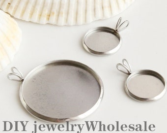 May include: Three silver-toned metal pendant trays with rounded edges and a loop for hanging. The trays are different sizes and are arranged on a white surface.