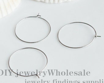 May include: Three silver hoop earrings, each with a diameter of approximately 1 inch. The earrings are on a white surface.