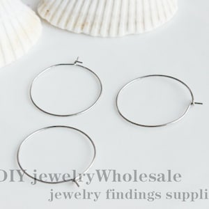 Peut inclure: Trois boucles d'oreilles en argent, chacune d'un diamètre d'environ 2,5 cm. Les boucles d'oreilles sont sur une surface blanche.