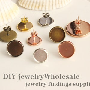May include: Assortment of earring settings in various finishes, including silver, gold, bronze, and rose gold. The settings are round and have a flat surface for attaching a cabochon.