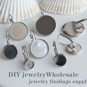 May include: A set of eight silver earring blanks with round, flat, metal bases. The bases are designed to hold a variety of materials, such as glass, resin, or fabric. DIY jewellery wholesale jewellery findings supplies.