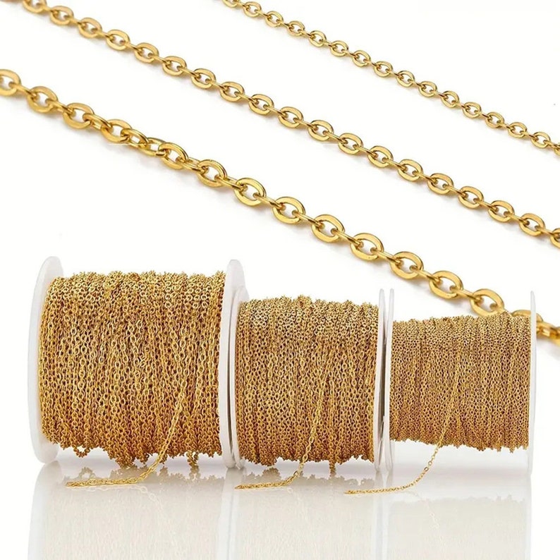 May include: Three spools of gold chain, each with a different size link. The chain is on white spools with a white background.