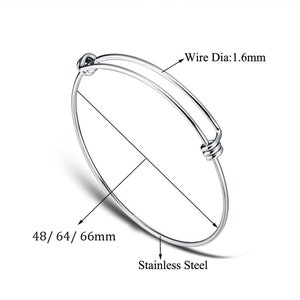 以下が含まれることがあります： 結び目の留め具が付いたシルバーのバングルブレスレット。ブレスレットの厚さは1.6mm、直径は48/64/66mmです。ステンレス製です。