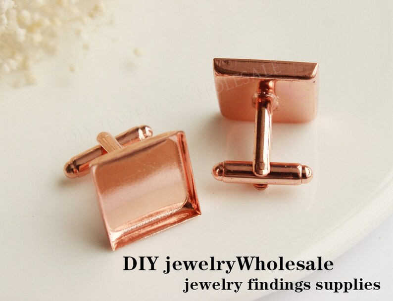May include: Two rose gold cufflinks with square settings. The cufflinks are made of metal and have a polished finish.