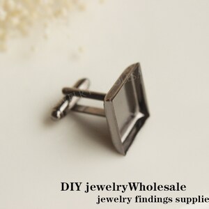 May include: A pair of silver cufflinks with a square glass bezel. The cufflinks are perfect for adding a touch of elegance to any outfit.
