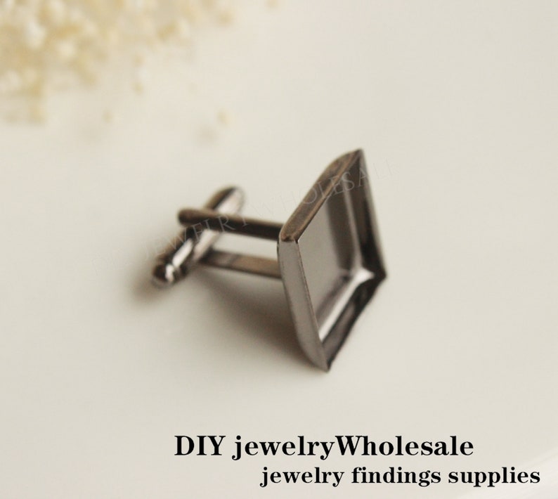 May include: A pair of silver cufflinks with a square glass bezel. The cufflinks are perfect for adding a touch of elegance to any outfit.