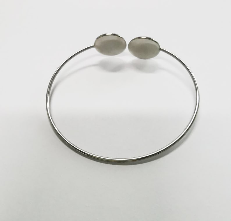 May include: A silver bangle bracelet with two round, flat, silver charms.