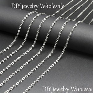 May include: A variety of silver chain links in different lengths, laid out on a black surface. DIY jewelry wholesale.