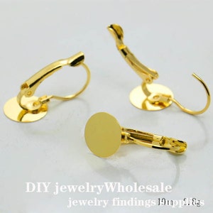 Op de afbeelding: Drie gouden oorbel-bevindingen met een ronde, platte basis en een clip-sluiting. DIY sieraden groothandel sieraden bevindingen 10mm 18gs.