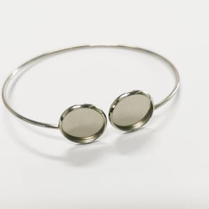 May include: Silver bangle bracelet with two round, clear glass cabochons.